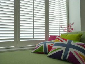 Multi-Coloured Union Jack Cushions Laying In Front Of White Window Shutters