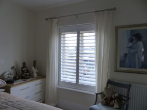 White Window Shutters In Bedroom With Sheer Cream Curtains