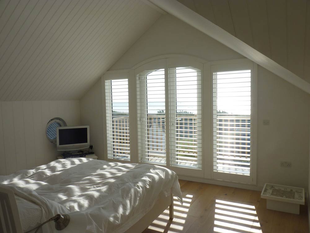 Large White Window Shutters Across Arched Balcony Doors