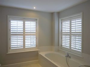 Two Large Bathroom Windows With White Shutter Blinds