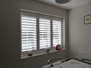 White Shutter Blinds In Three Panel Window In Dining Room